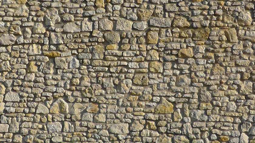 Mur construit avec des pierres de différentes tailles et couleurs, sans jointure visible