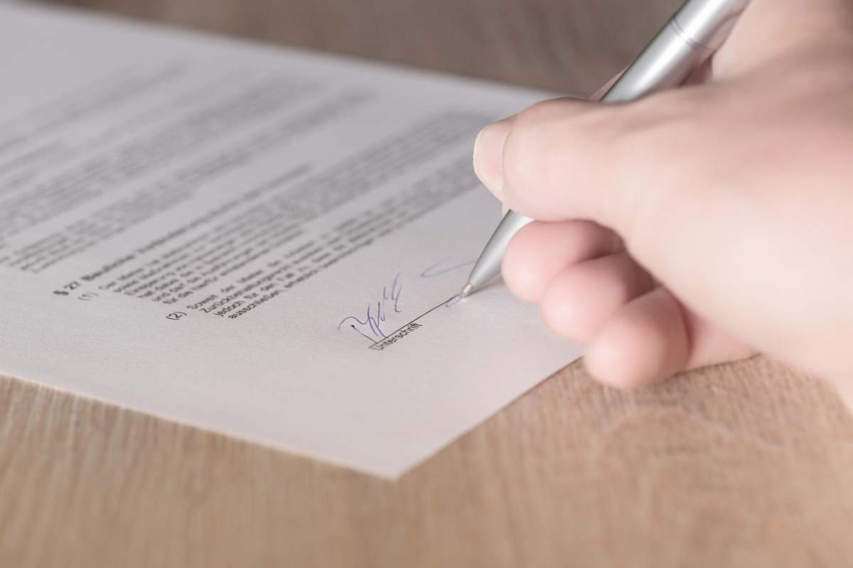 Main signant un document commercial sur une surface en bois