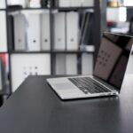 Un ordinateur portable sur un bureau avec des classeurs derrière