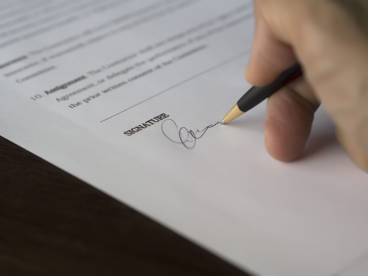 main écrivant signature sur document avec stylo à bille