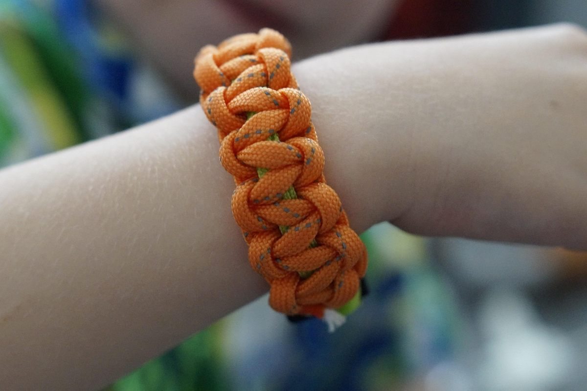 Bracelet de survie en paracorde orange tressée porté au poignet